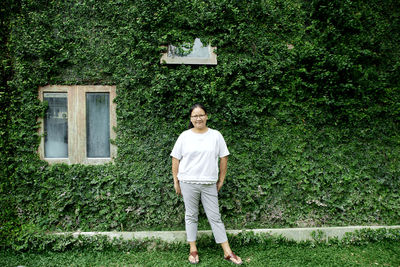 Portrait of woman standing against ivy