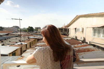 Rear view of woman with buildings against sky