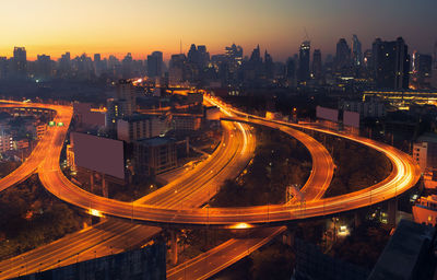 High angle view of light trails on road amidst buildings against sky at night