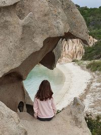 Rear view of man sitting on rock