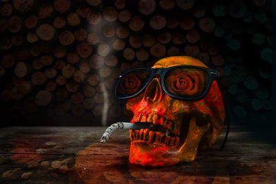 Close-up of human skull with cigarette and sunglasses on table