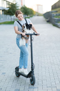 Portrait of smiling young woman with luggage walking on street