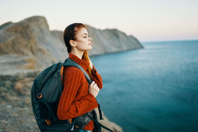 Man looking away while standing by sea against sky