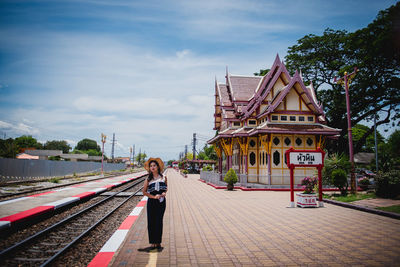 Woman on railroad tracks against sky