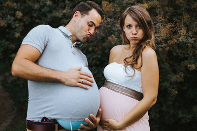 Pregnant woman making face while holding husband stomach