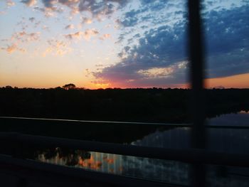 Silhouette trees by lake against sky during sunset