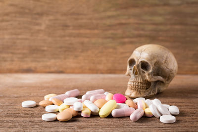 Close-up of human skull and medicines on wooden table