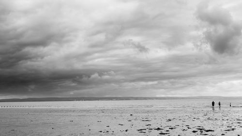 Silhouette people on beach against sky