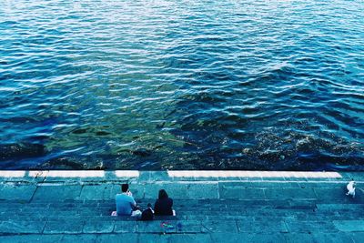 High angle view of couple sitting on steps at riverbank