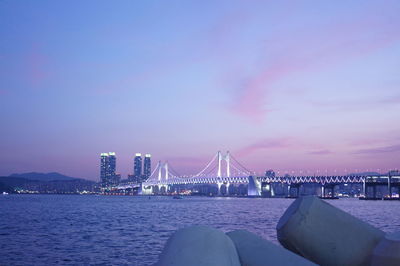 View of suspension bridge in city at dusk