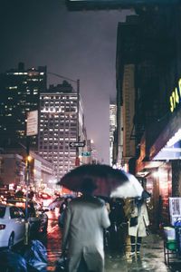 Rear view of people standing on street at night