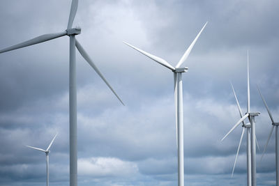 Low angle view of windmills against sky