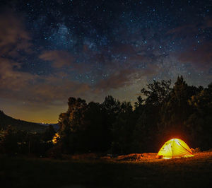 Illuminated tent on field against sky at night