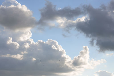 Low angle view of sunlight streaming through clouds