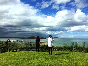 Rear view of man and woman standing by sea against sky