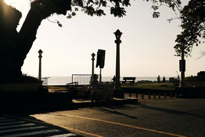 Street by silhouette city against clear sky