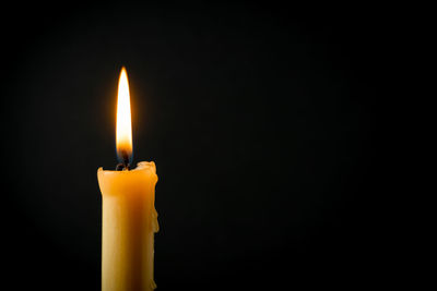 Close-up of burning candle against black background