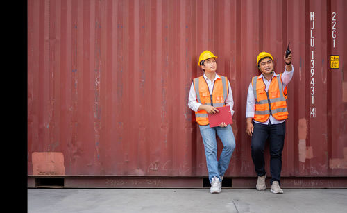 Portrait of friends standing against red wall