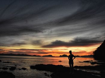 Silhouette man standing on beach against sky during sunset