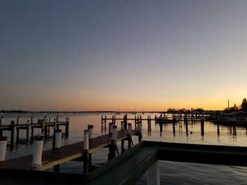 Pier on sea against clear sky during sunset