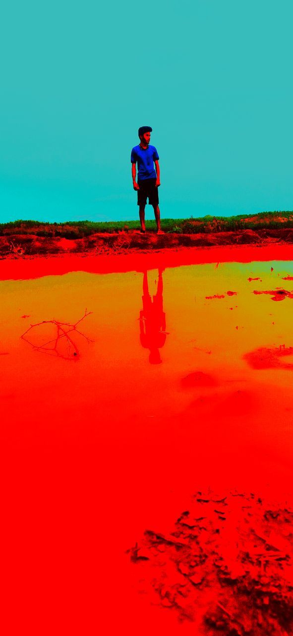 FULL LENGTH OF MAN STANDING ON RED UMBRELLA