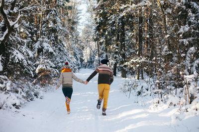 Rear view of people walking on snow covered land