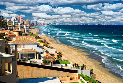 View of beach against cloudy sky in city