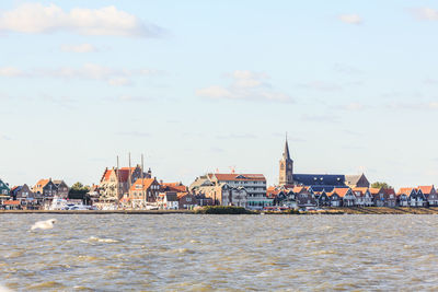 View of buildings by sea against sky