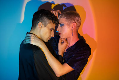 Portrait of gay couple wearing makeup and embracing in illuminated studio