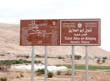 Information sign on field against sky