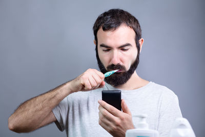 Man holding mobile phone against gray background