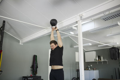 Low angle view of young man exercising with kettlebell at gym