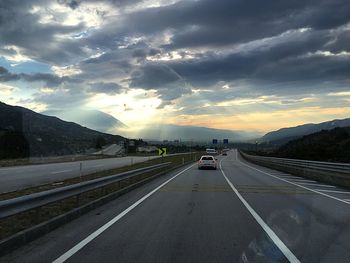 Road passing through mountain against cloudy sky