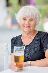 Mature woman sitting at a table in a summer cafe and drinking beer