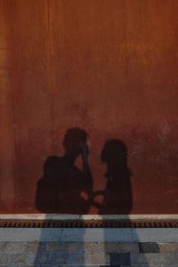 Shadow of man and woman sitting on swimming pool