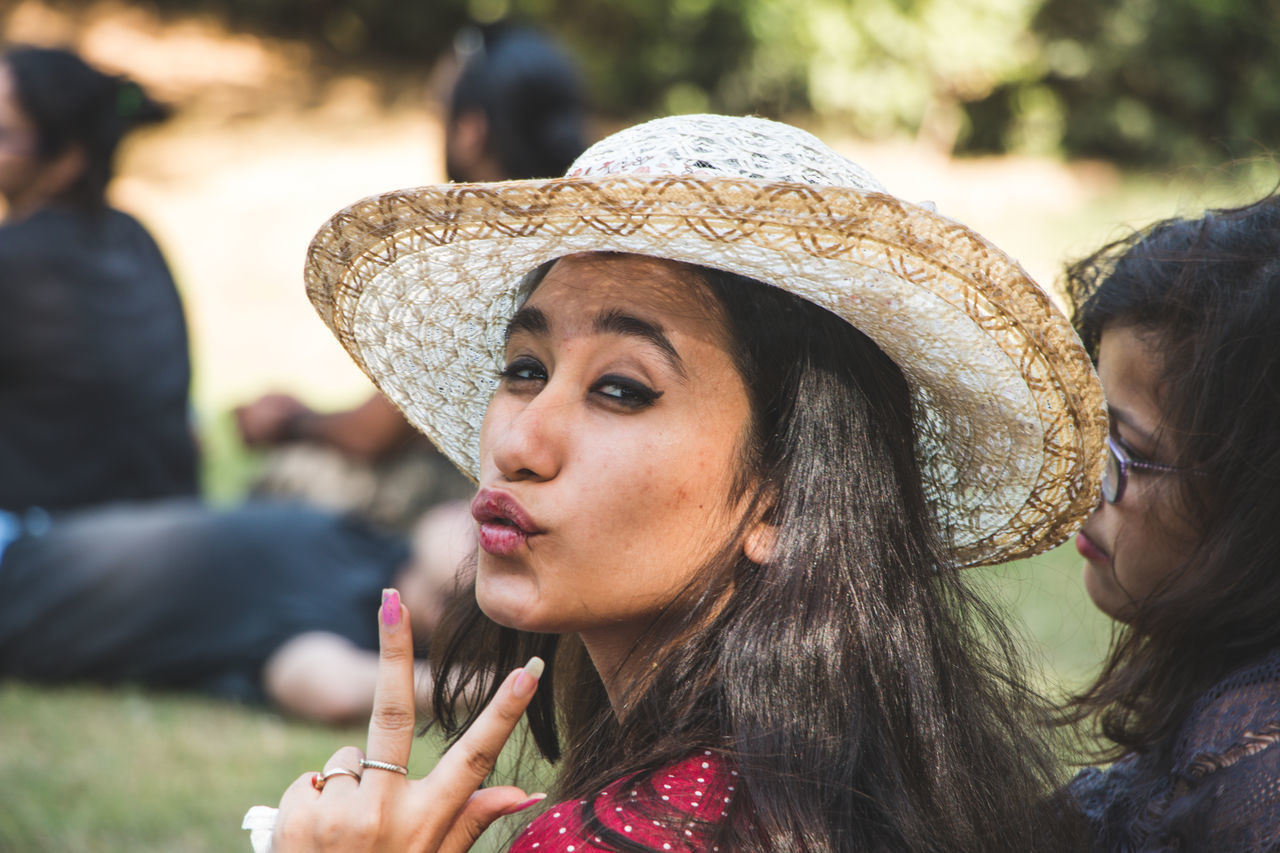 real people, headshot, lifestyles, leisure activity, portrait, women, focus on foreground, young adult, hat, adult, young women, clothing, people, incidental people, day, close-up, looking, looking away, hairstyle, outdoors