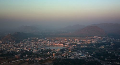 Nature theories, pushkar, india- high angle view of townscape and mountains against sky