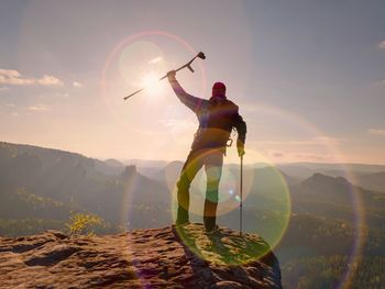 Rear view of man standing on mountain against sky