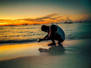 Man on beach against sky during sunset