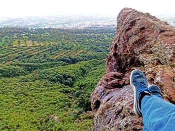 Low section of man on cliff against sky