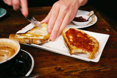 Cropped image of man applying butter on bread in plate