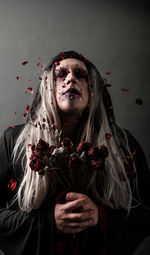 Portrait of beautiful young woman standing against red wall during halloween