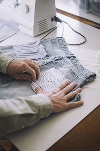 Hands of fashion designer adjusting back pocket on jeans at workshop