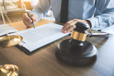 Midsection of man reading book on table
