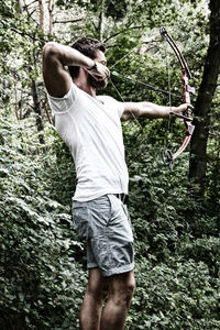 Man holding tree trunk in forest