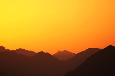Scenic view of silhouette mountains against orange sky