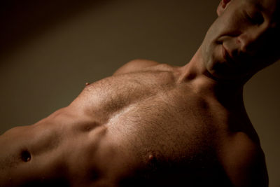 Young man shirtless closeup working out, muscular body part with soft light