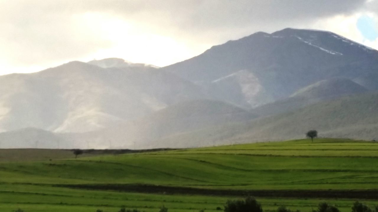 landscape, mountain, tranquil scene, tranquility, scenics, beauty in nature, sky, field, mountain range, nature, grass, rural scene, green color, idyllic, non-urban scene, sun, cloud - sky, sunbeam, grassy, agriculture