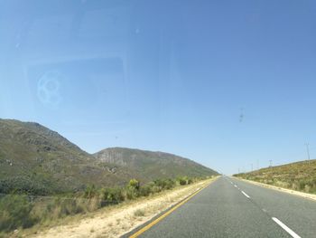 Road by mountains against clear blue sky