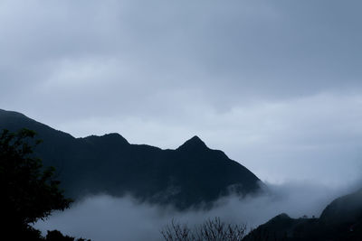 Clouds covering silhouette mountains